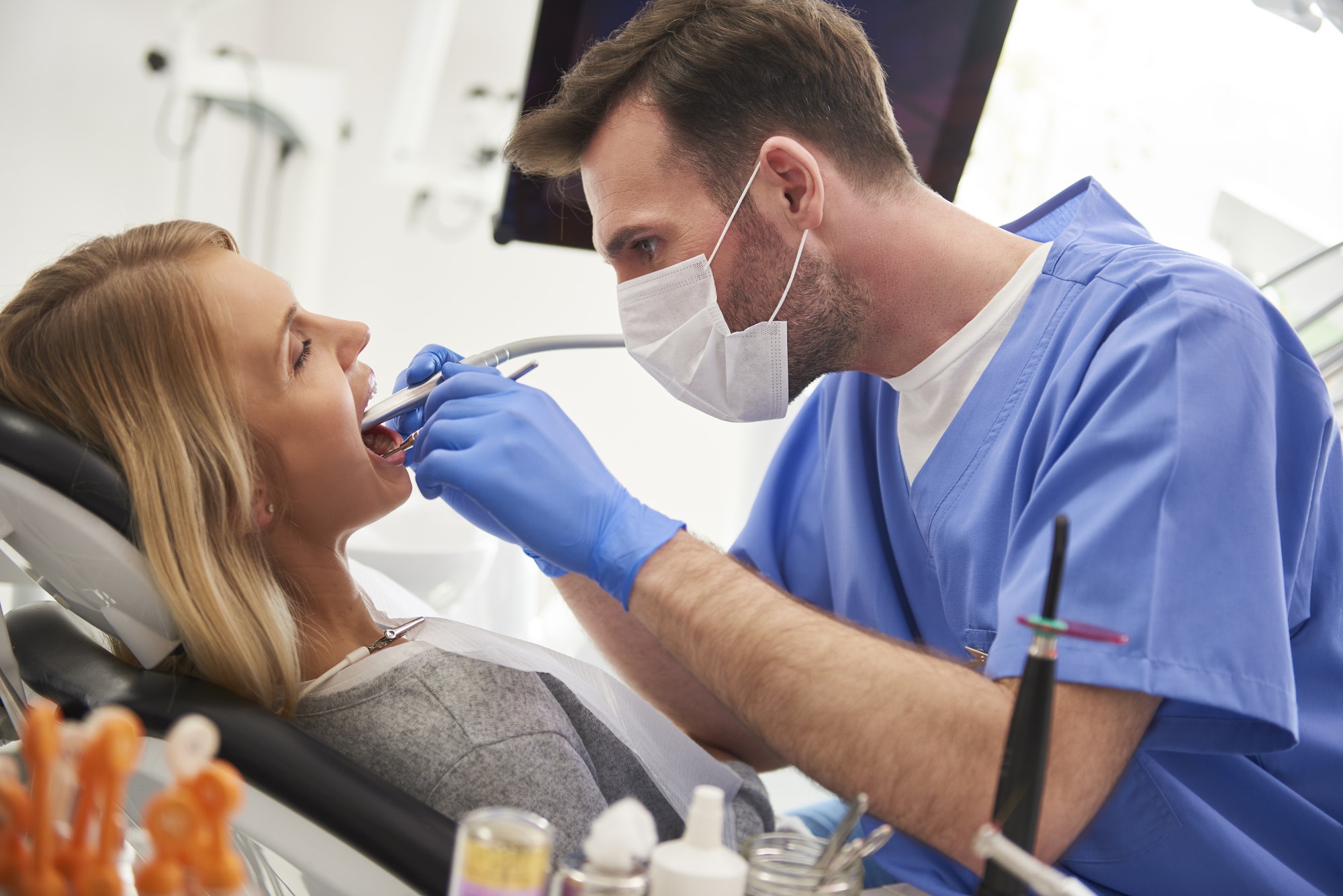 focused stomatologist using dental drill and dental mirror